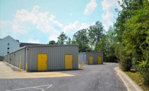 exterior view of AA Self Storage buildings with yellow doors and surrounding trees in Jacksonville NC