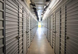 long brightly lit hallway lined with white roll-up storage unit doors at AA Self Storage facility in Jacksonville NC